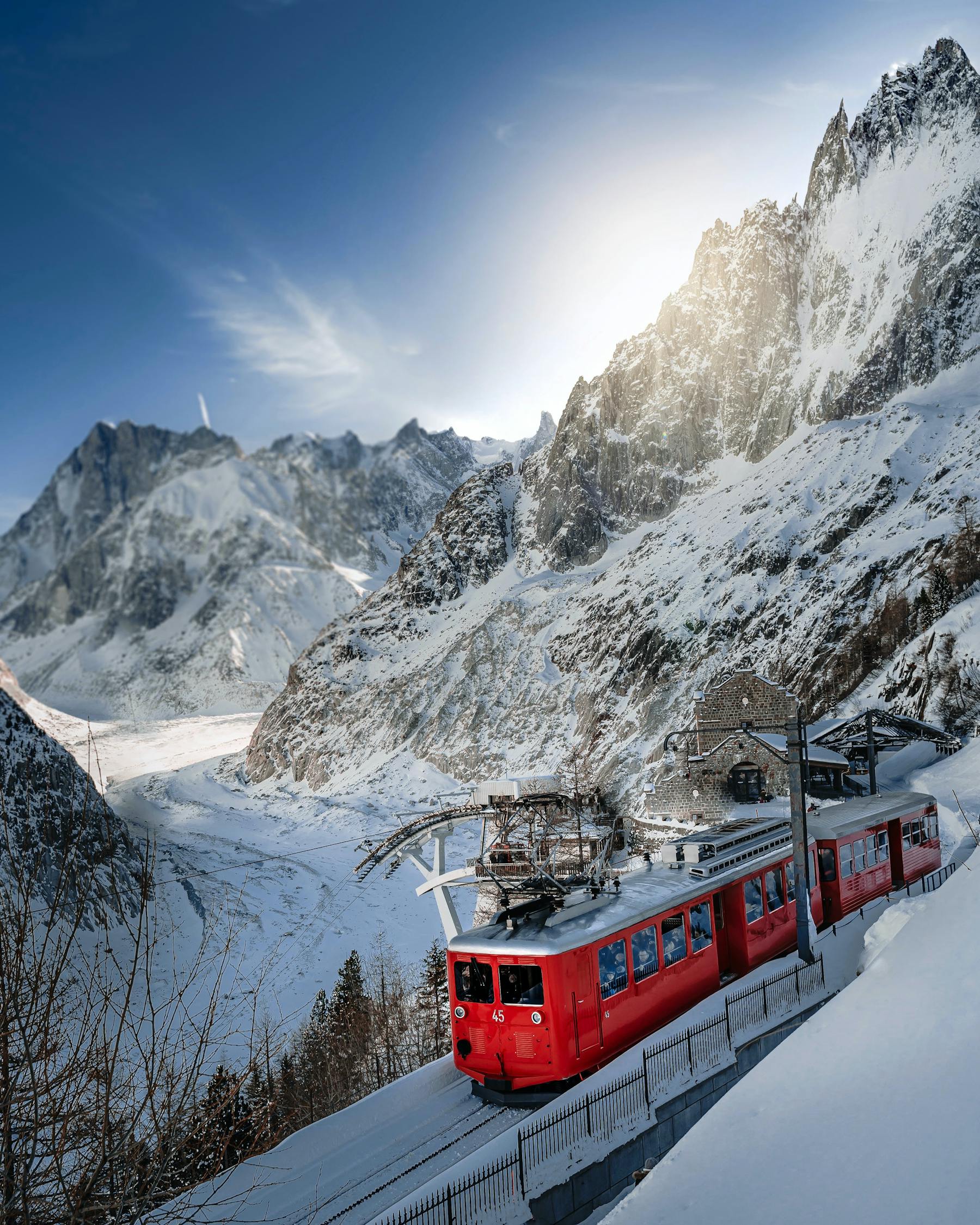 The red Montenvers train pulling into its station in winter, above the snow-covered Mer de Glace and the walls around it